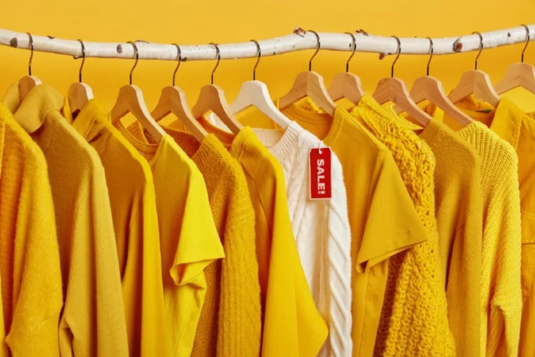 cabide com diversas camisetas amarelas e uma branca entre elas com desconto