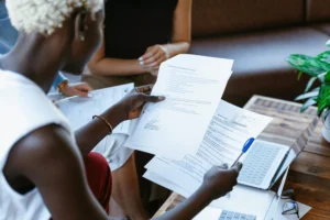 Reunião de trabalho em que uma pessoa segura documentos com texto impresso enquanto discute algo com colegas.