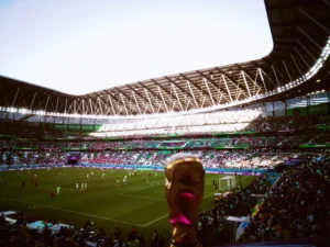 Vista panorâmica de um estádio durante a Copa do Mundo, com o troféu do torneio em destaque próximo ao campo